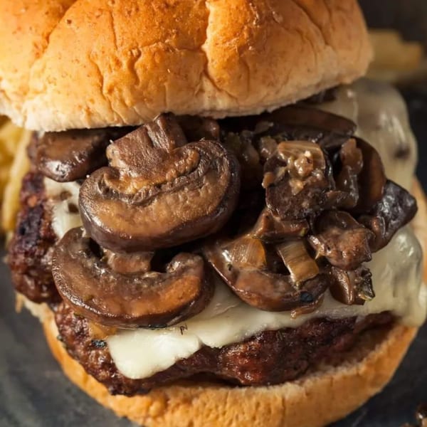 Close-up of a Burganic Hub mushroom and Swiss burger with a toasted bun.