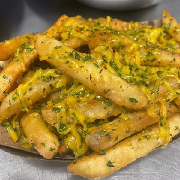 Golden-brown Burganic Hub fries generously topped with melted cheese and fresh green herbs.