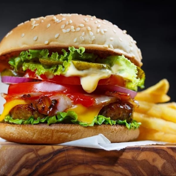 A delicious Burganic Hub burger with melted cheese, fresh vegetables, and a side of fries.
